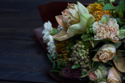 En närbild av en bukett med olika blommor och gröna blad.