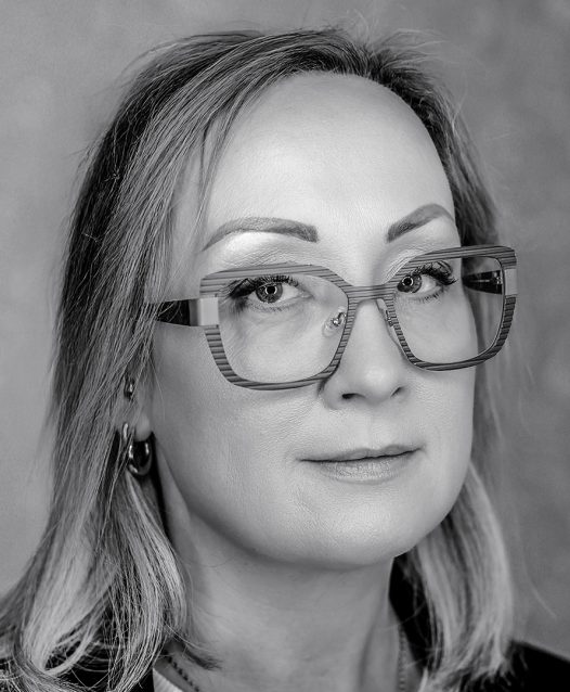 Kvinna med glasögon och axellångt hår ser in i kameran.
